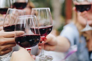 A group of people clinking glasses of red wine in a toast.