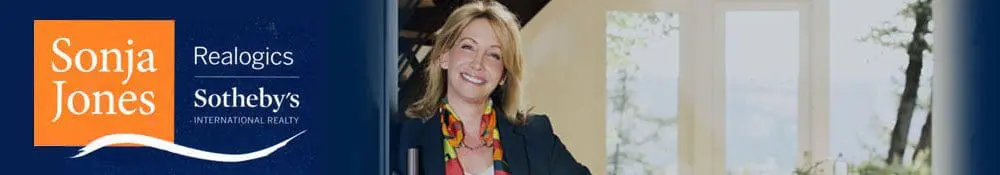 A smiling woman stands near an open door, with a Realogics Sotheby’s International Realty advertisement on the left side featuring the name Sonja Jones.