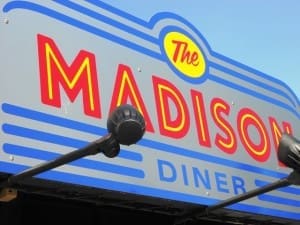 Sign for "The Madison Diner" with bold red and yellow lettering on a gray and blue background.