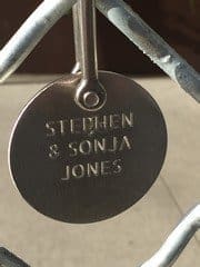 A metal tag engraved with "Stephen & Sonja Jones" is attached to a chain-link fence.