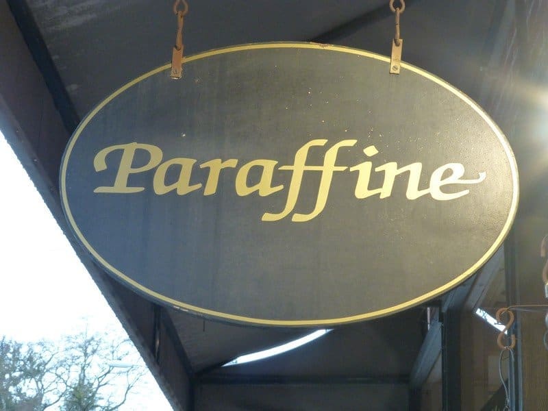 An oval sign with the word "Paraffine" written in cursive font hangs outside, under an awning.