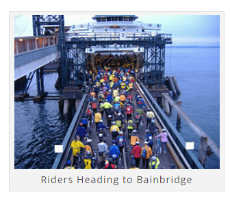 A large group of cyclists in colorful attire boarding a ferry at a dock. The caption reads, "Riders Heading to Bainbridge.