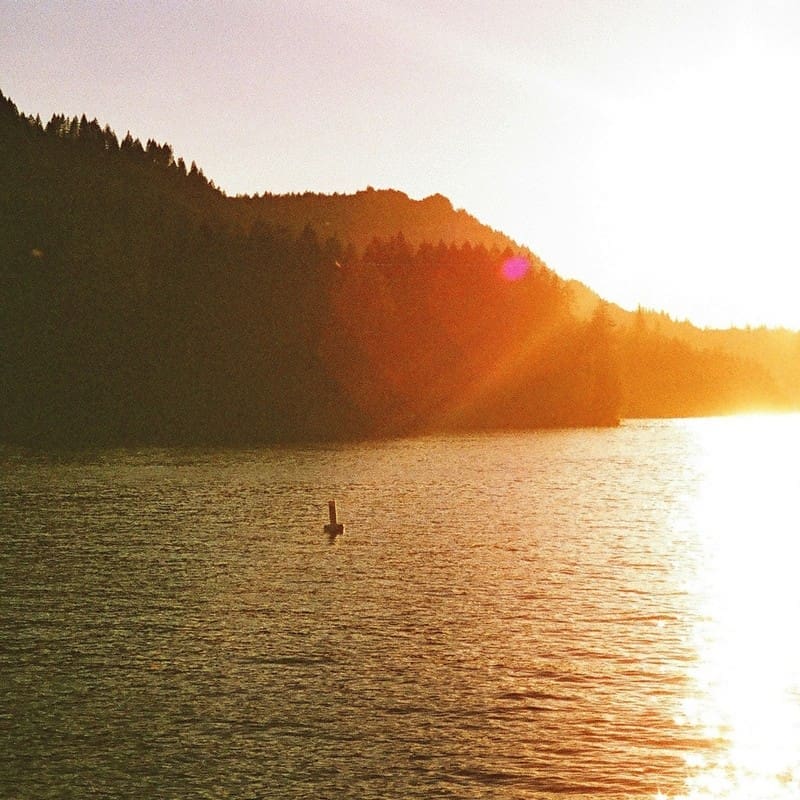 Sunset over a lake with a buoy.