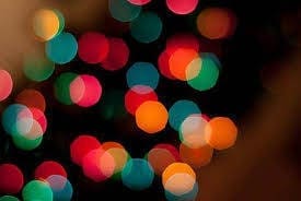 Blurred colorful lights on a dark background, creating a bokeh effect with red, green, orange, and blue hues.