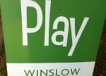 A green and white sign that reads "Play" at the top and "Winslow" at the bottom.