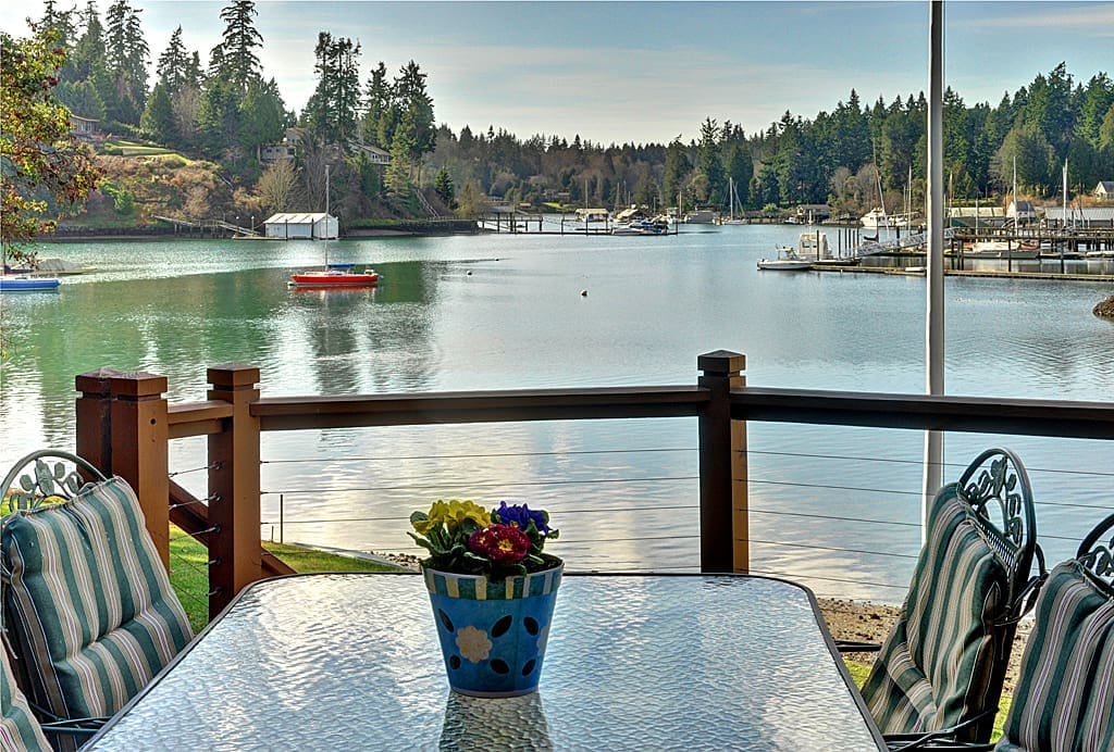 Waterfront patio with flowers and a view.