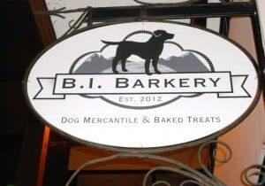 Sign for "B.I. Barkery" featuring a dog's silhouette with a mountain backdrop, established in 2012. Below the establishment name, it reads "Dog Mercantile & Baked Treats.