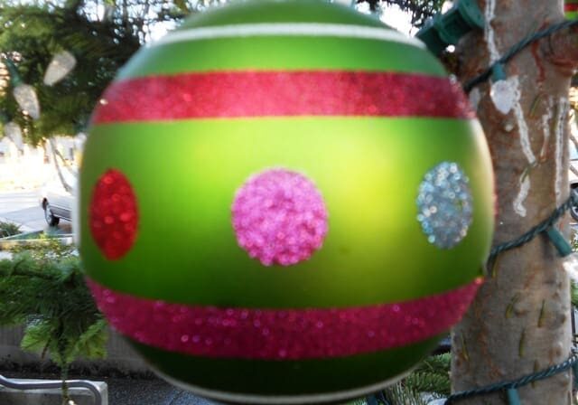 Green Christmas ornament with pink and silver accents.