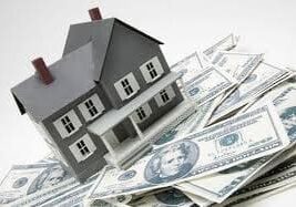 Model house placed on a pile of U.S. dollar bills.