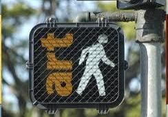 A pedestrian signal showing a walking figure overlaps with the word "art" in yellow letters. The signal is covered by a wire mesh.