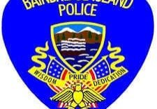 Logo of the Bainbridge Island Police featuring an eagle, U.S. flags, and a shield with mountains and water. Text reads: "Bainbridge Island Police" and "Wisdom, Pride, Dedication.