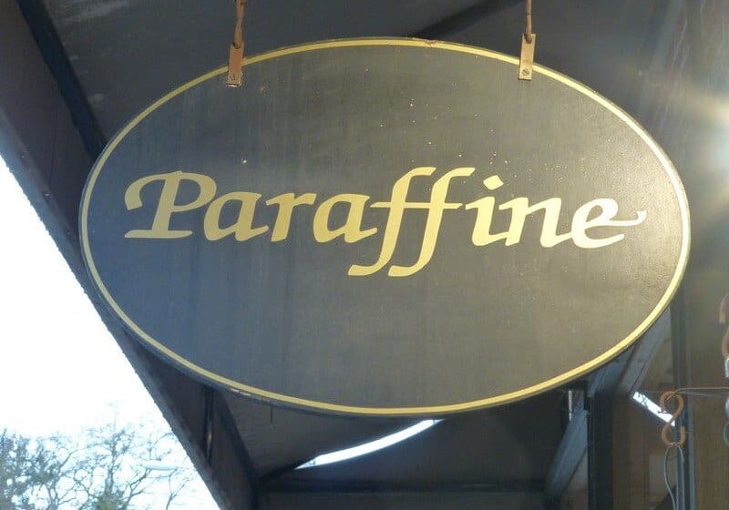 An oval sign with the word "Paraffine" written in cursive font hangs outside, under an awning.