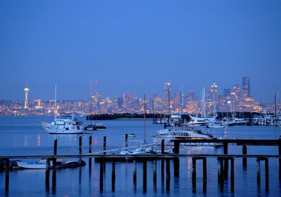 Seattle skyline at dusk with boats docked.