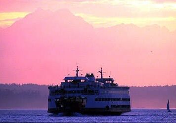 Ferry sailing at sunset with mountains in background.